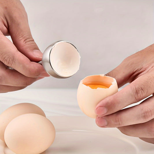 Händer som öppnar ägg med Kitchlark äggknäckare, äggula synlig i skalet